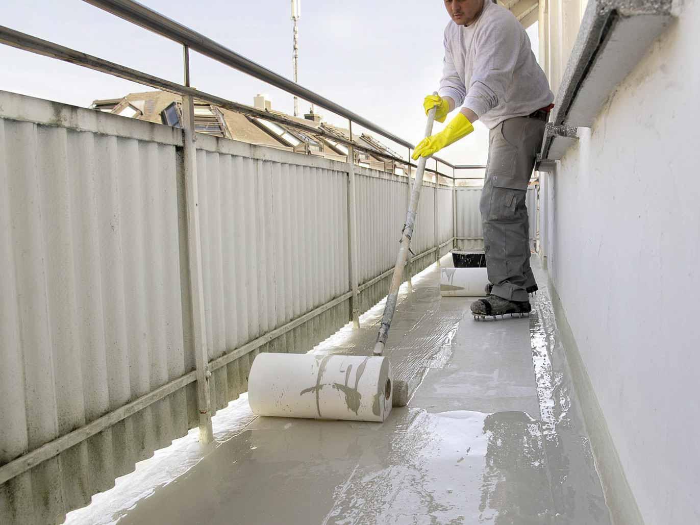 Ausrollen von Vließ in der Abdichtungsschicht auf Balkon.