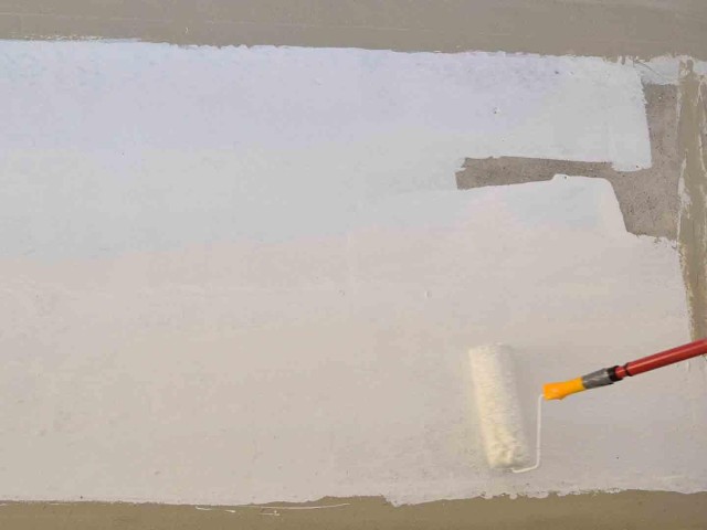 Auftragen weißer Grundierung auf Balkonboden.